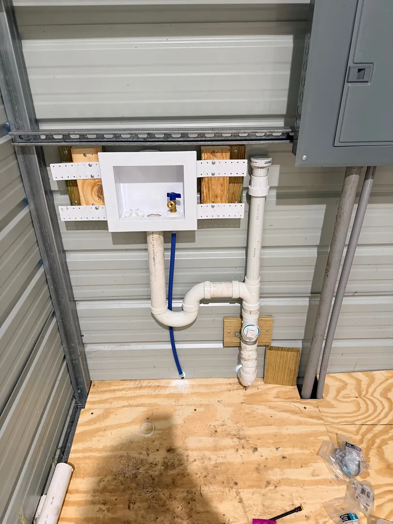 New washing machine outlet box with PVC drain and standpipe on a metal building wall
