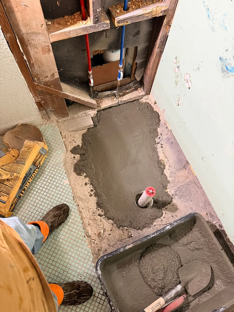 Concrete patched back over an under-slab plumbing repair in a bathroom
