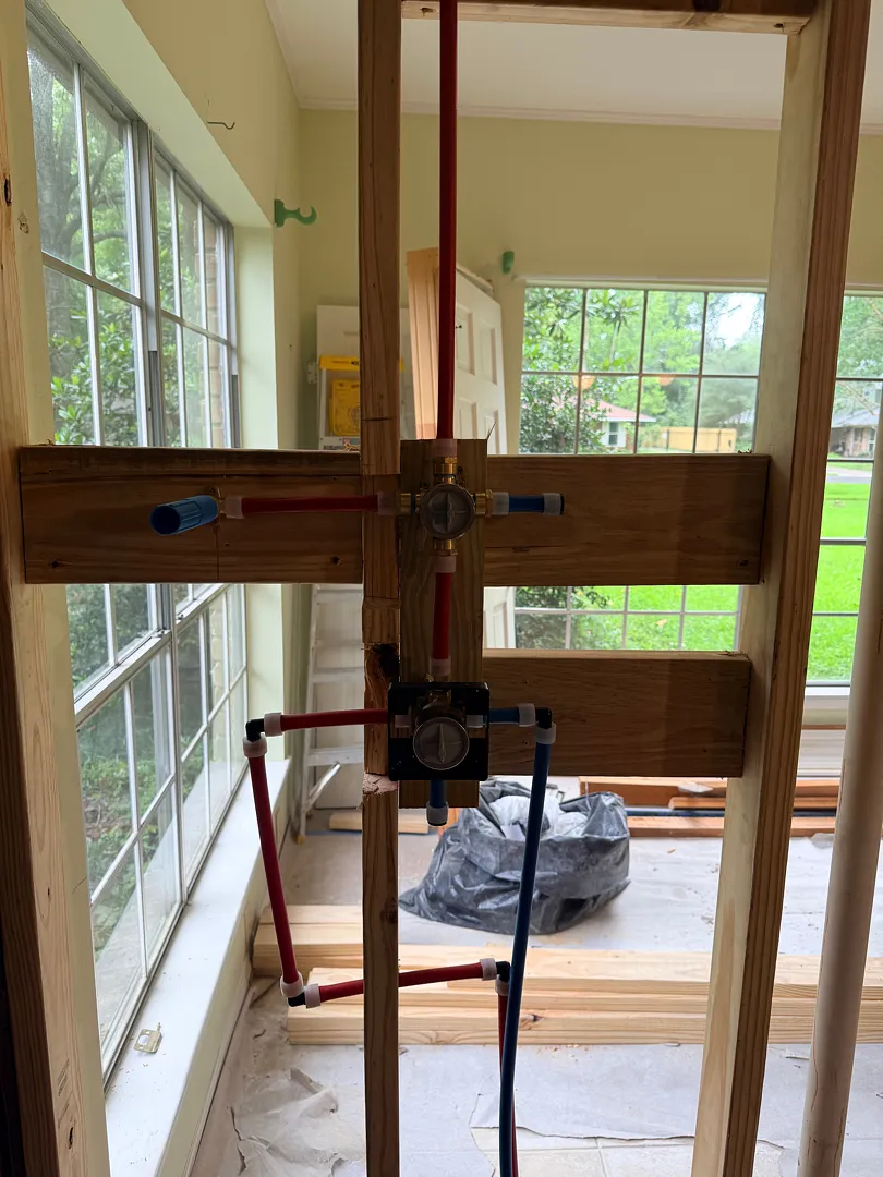 Two shower mixing valves rough-in with red and blue PEX supply lines