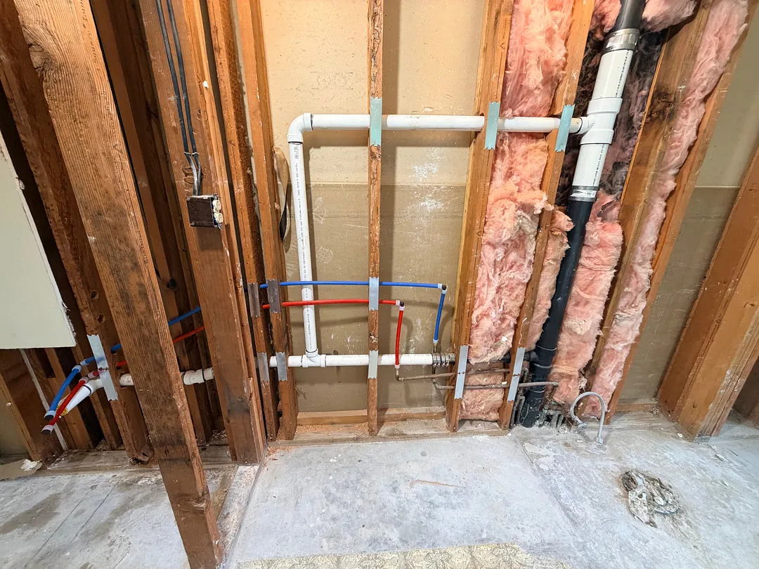 Open wall showing new PEX and PVC drain rough-in plumbing